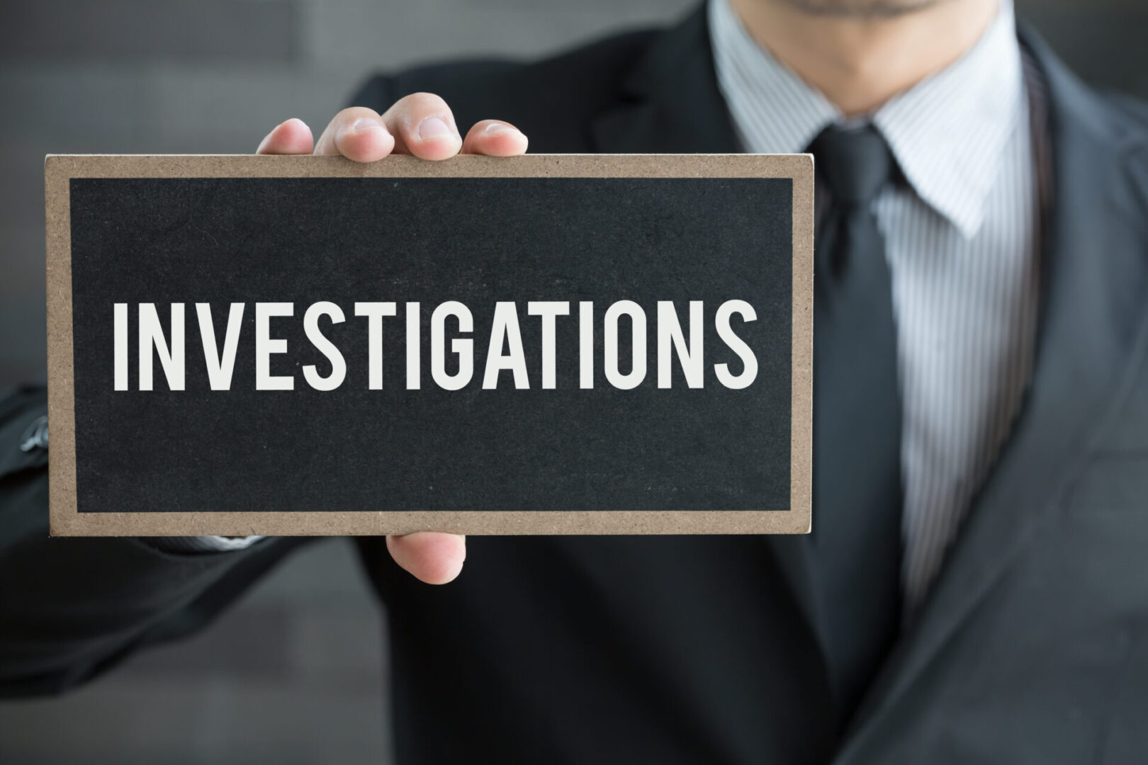 Investigations, message on blackboard and hold by businessman